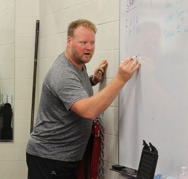 Powerlifting head coach Scott Russell goes over the team’s workout on the whiteboard during practice Thursday morning. The powerlifting team enters its second year of existence under Russell. 