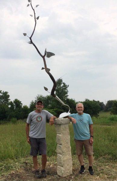 Gary Hinman standing alongside his sculpture with Bill Gordon, who made the base for the sculpture, installed it and contributed stonework. Photo courtesy of The Lawrence Times.