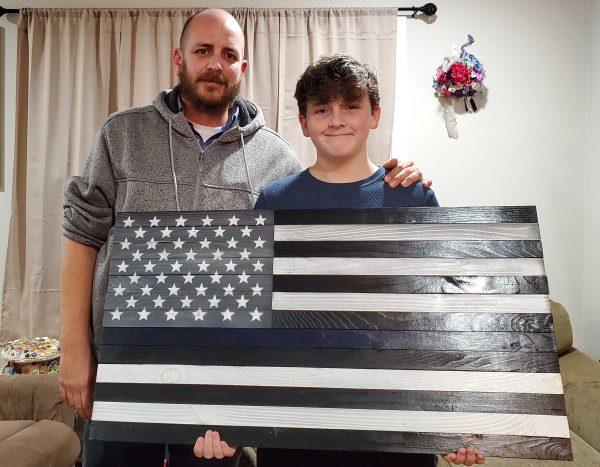 Sean Mower and Aiden show one of the wooden flags they have worked on.