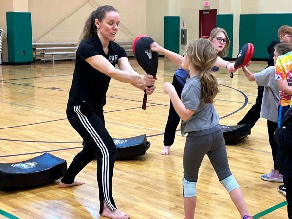 Tonya Bolte holds a punching glove for Haddie Wilhelm during the taekwondo demonstration.