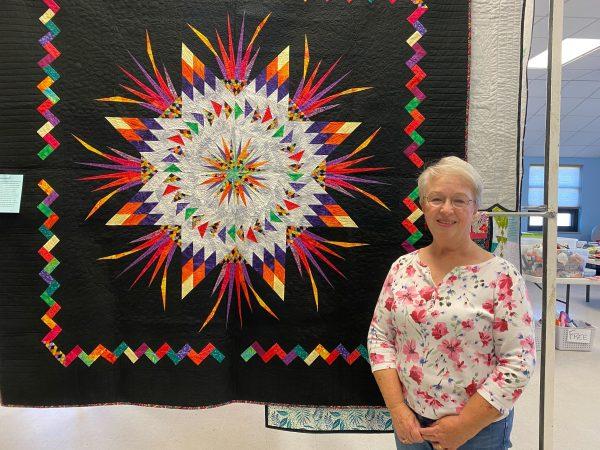 Debbie Coddington stands in front of one of her favorite quilts that she made.