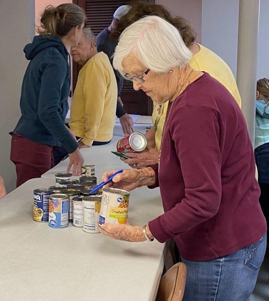 Donna Brown, a 15-year veteran of the food drive, checks the dates on the canned goods Saturday.