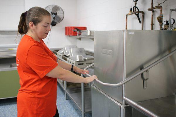 Lori Walker, kitchen manager at the Early Learning Center, washes dishes Thursday morning. Walker is preparing to serve breakfast and lunch to over 100 students on Monday.  