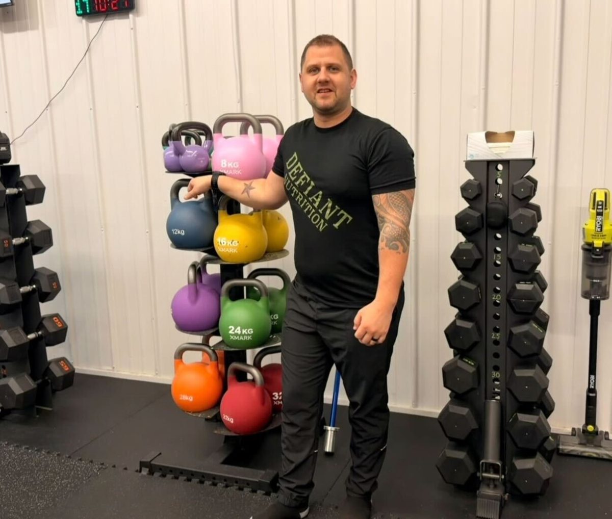 Ty Hendon stands in front of workout equipment on Friday at the Defiant Fitness studio.
