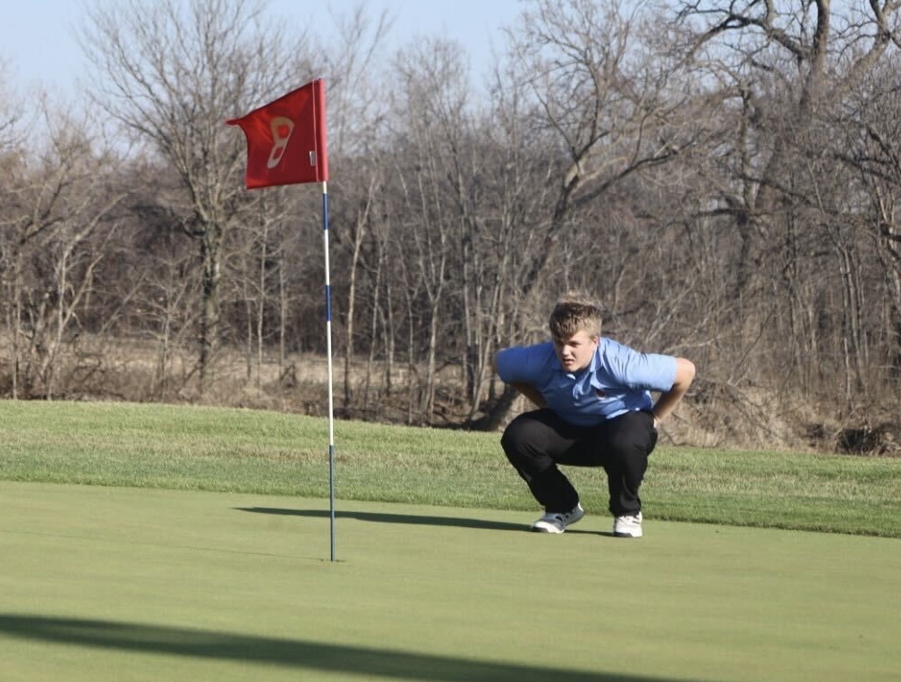 Junior Luke Watts examines the putting green during practice Wednesday. 