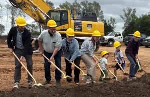 Developer GW Weld, left, breaks ground with his family. He thanked his family for all their sacrifices as he’s had to spend late nights in meetings.